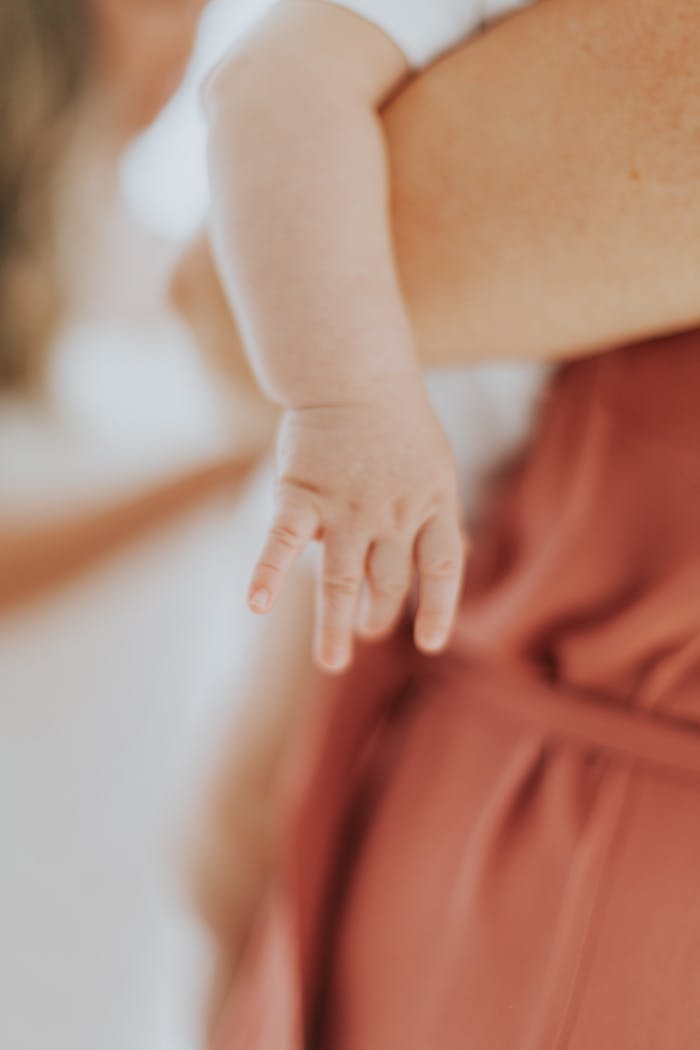 Tender close-up of a mother lovingly holding her newborn's arm.