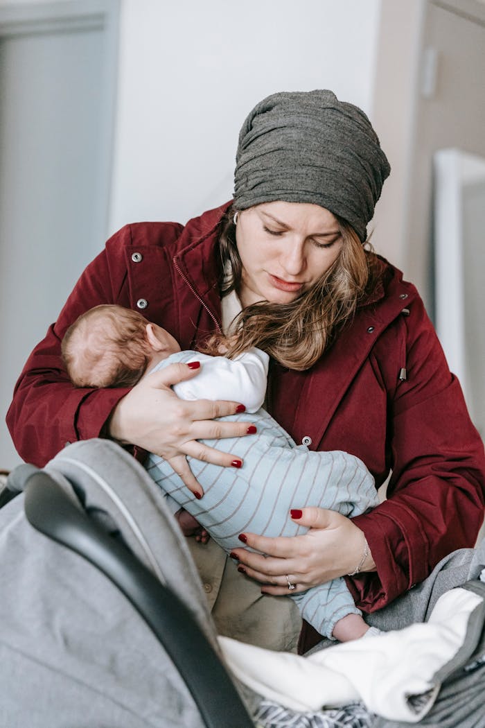 A caring mother cradling her infant child indoors, showcasing warmth and affection.